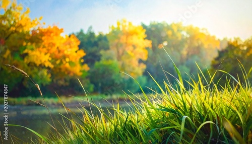Vibrant green grass and colorful autumn trees reflect serenely in a calm lake at sunset