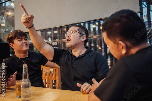 Foto A man reacts and points, showing surprise, shock, tension, and emotional stress after spotting his ex, expressing mixed feelings, awkwardness at the bar while his friends watch and calming him