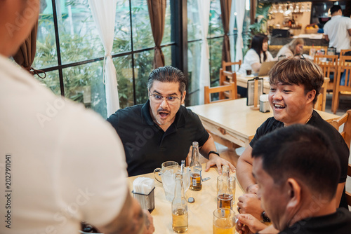 Photos A man reacting with surprise with his friends at the bar while drinking beer, re