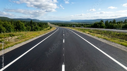 Scenic asphalt road passing through vast green mountain landscape under blue sky