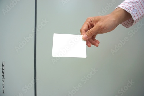 Cuadro en lienzo Hand holding blank white business card on gray background