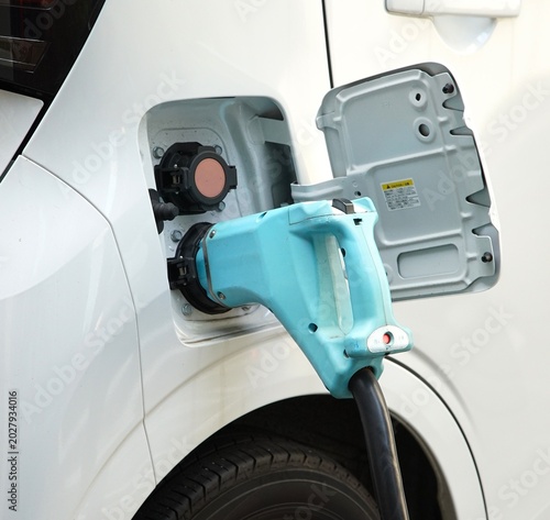 Electric vehicle connected to public fast charging station via blue plug for battery recharging