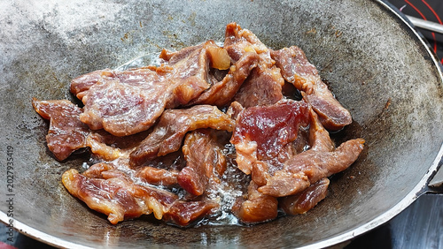 Quadro su tela Beef Strips Sizzling in a Pan: Close-up shot of raw beef strips sizzling in a metal pan, ready for cooking