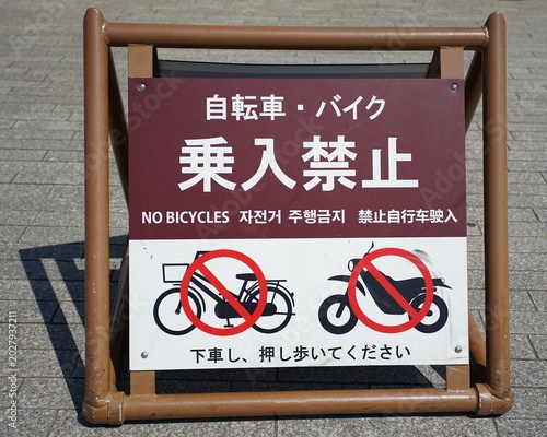 Tableau sur toile A ground-level sign prohibiting bicycles and motorcycles, instructing users to d