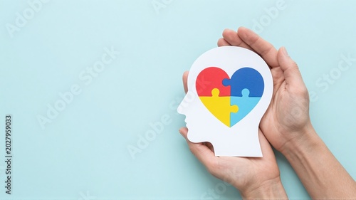 Hands holding head with puzzle heart for neurodiversity on background