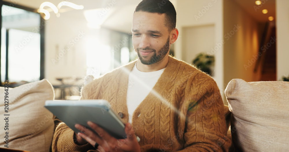 Fototapeta premium Tablet, relax and man in home for reading ebook, online search and entertainment on sofa. Tech, smile and person at living room for social media profile, browsing internet or news with information