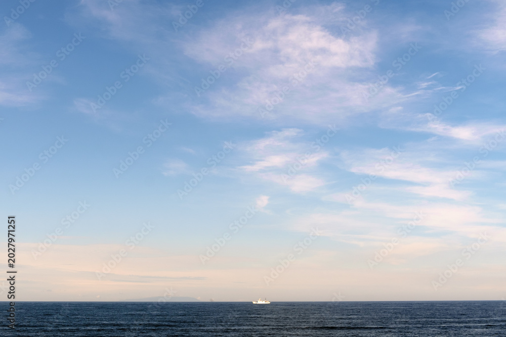 Fototapeta premium 小さな船が浮かぶ穏やかな水平線と青空