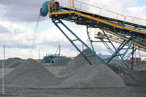 Foto Process of dropping gravel from industrial conveyor belt onto heap at mineral op