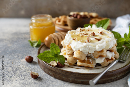 Belgian waffles with ricotta cheese, honey and hazelnuts for breakfast on a stone background. Sweet breakfast gluten free. Summer homemade recipe. Copy space.