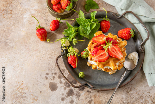 Belgian waffles with ricotta cheese and fresh strawberries for breakfast on a stone background. Sweet breakfast gluten free. Summer homemade recipe. Copy space.