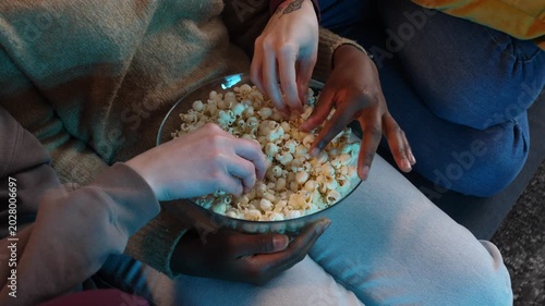 Diverse friends sharing popcorn while watching movie