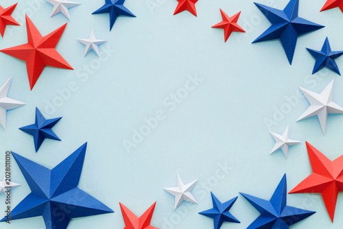 Red white and blue paper stars with curled ribbons on light blue background, patriotic holiday border with copy space. Design element.