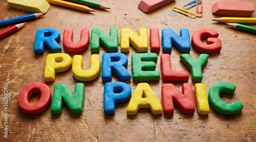 Vibrant 3D letters spelling 'Running Purely on Panic' surrounded by school supplies, humorously depicting the intense pressure of academic deadlines and work demands