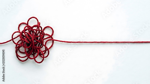 Tangled red string on white background with clear space