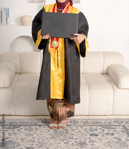 Faceless female body wearing a toga at graduation while holding a blank black folder