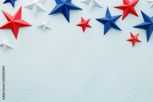 Red, white and blue origami paper stars on a light blue background with large copy space, ideal for patriotic advertising, holiday promotions, greeting cards, invitations, banners, posters, social