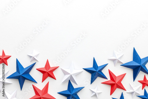 Red, white and blue origami paper stars on white background with large copy space, ideal for patriotic advertising, holiday promotions, greeting cards, invitations, banners, posters, social media