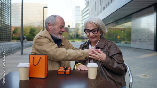 Senior couple arguing then reconciling at a cafe