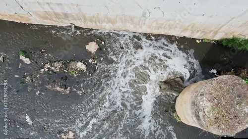 An Aerial View of Drainage Pipe Pouring Murky Foul Smelling Water into Polluted Canal Environment