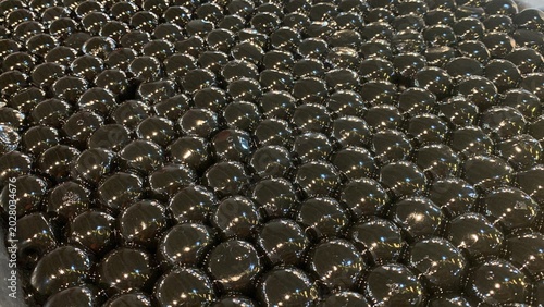 Glossy black tapioca pearls, often referred as giant boba pearls on aluminum tray, infused with flavors like brown sugar or caramel to enhance their taste. commonly used in specialty bubble tea drinks