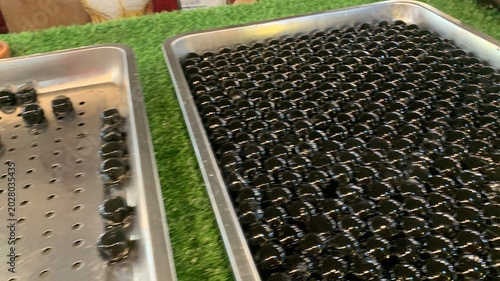 Quadro su tela Glossy black tapioca pearls, often referred as giant boba pearls on aluminum tray, infused with flavors like brown sugar or caramel to enhance their taste