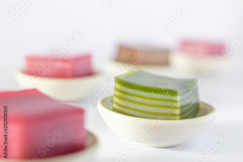 Steamed pandan layer cake in small cups on a white background.