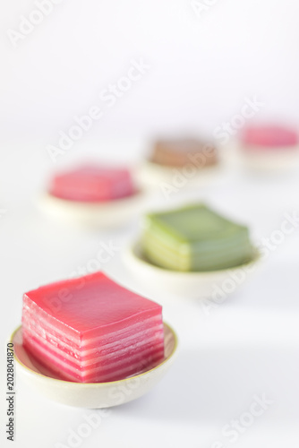Steamed pandan layer cake in small cups on a white background.