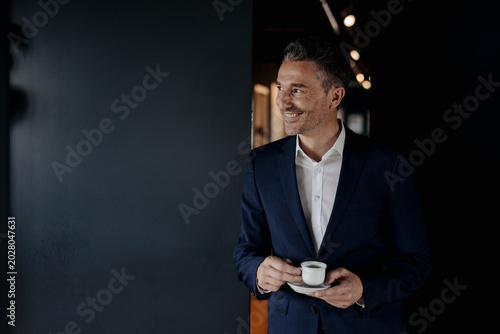 Smiling businessman with espresso cup looking sideways