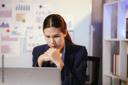 Bild auf Leinwand Stressed businesswoman suffering from headache and fatigue while working overtime at night in modern office workspace