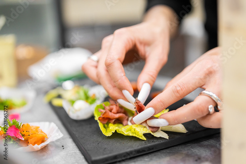 Obraz na plátně Chef with long manicured nails placing thinly sliced roast beef onto a fresh let