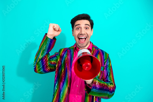Joyful showman in a bright colorful disco jacket shouts into a red megaphone at a lively party event