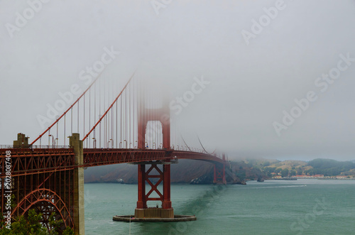 USA California Golden Gate Bridge in fog with tower partly hidden, ocean view and sailing boat in San Francisco