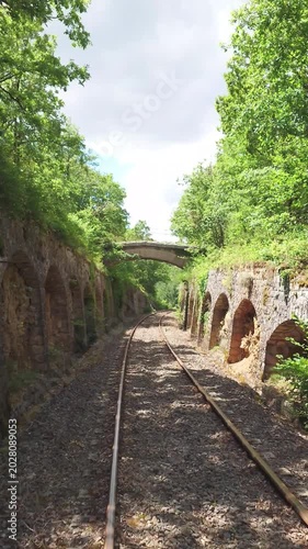 South France Larzac railbike adventure POV through ancient railway tunnel opening to a wide panoramic lush mountain valley view with train track details b roll stock video