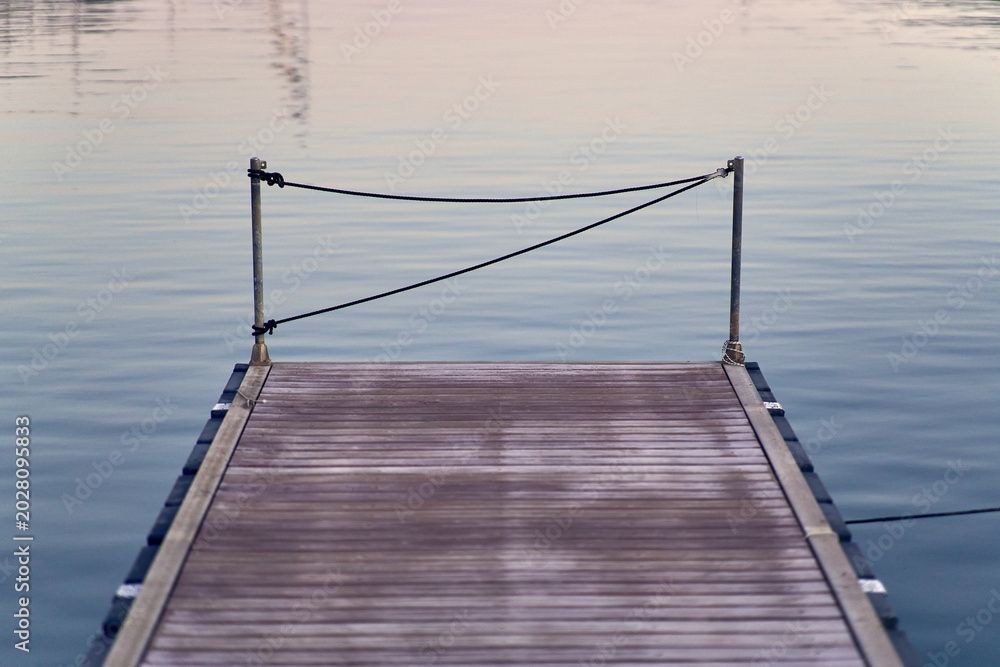 Fototapeta premium Wooden pier extending into calm reflecting water