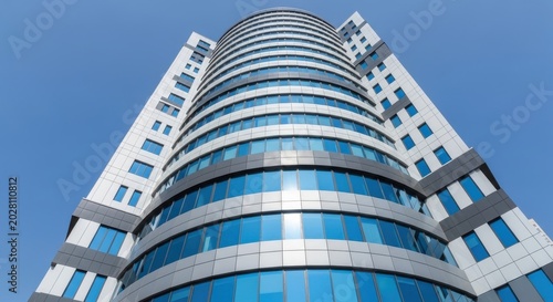Modern skyscraper building with curved facade and blue windows against clear sky