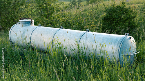 Old Galvanized Metal Storage Tank Abandoned in Overgrown Meadow, Rural Germany