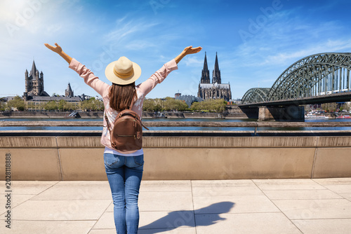 Foto A happy tourist woman with a backpack looks at the panoramic skyline of Cologne,