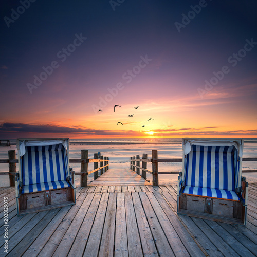 sunset on the beach with rustic beach chairs