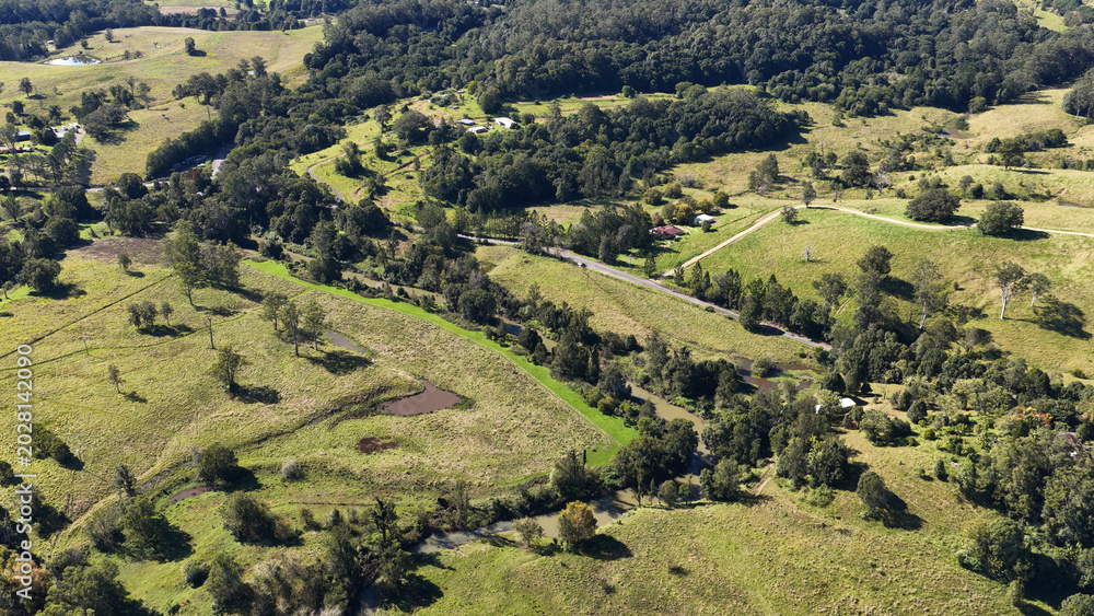Fototapeta premium Aerial View of Lush Green Rolling Hills and River in Nimbin