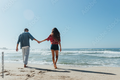 A couple walking hand in hand along the coast
