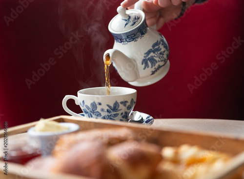 Pouring Fragrant Tea Into a Delicate Cup With Freshly Baked Treats Nearby