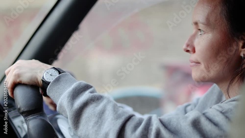 A middle-aged woman drives a car. She carefully monitors the road conditions through her rearview mirrors, assessing the road conditions for safe driving. Close-up 4K footage.