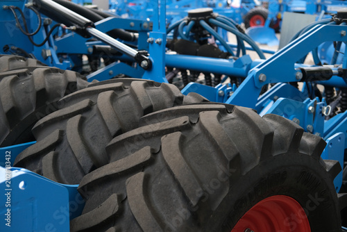 Close view of blue agricultural machinery with large tires, metal frame and hydraulic linkages, ready for field work and cultivation tasks.