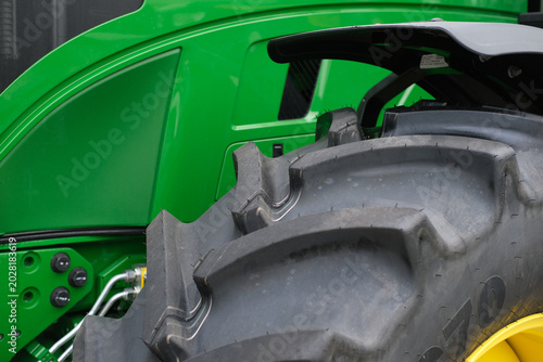 Close up of a green tractor with large tire, highlighting rugged farm machinery and agricultural equipment used for farming tasks in fields during harvest season.
