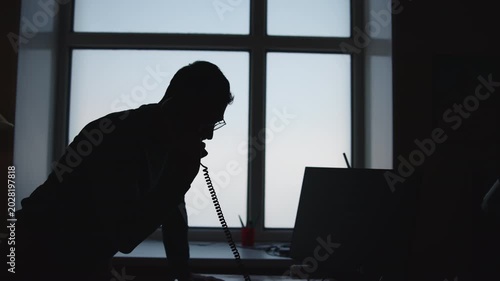 Individual Seated At Windowed Workstation Engrossed In Important Phone Call With Serious Intent. Media