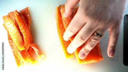 A professional close-up of a chef slicing a fresh salmon fillet on a white cutting board, showcasing culinary precision and the vibrant, healthy texture of the raw fish.