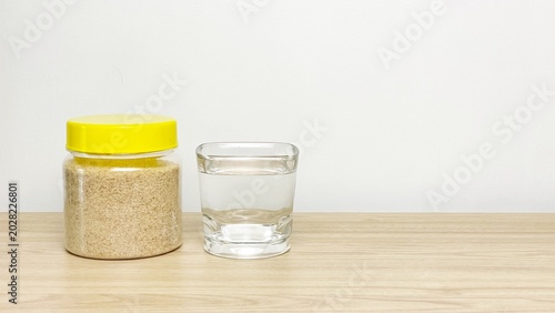 Foto A jar of psyllium husk and a glass of water on a wooden surface against a neutral background