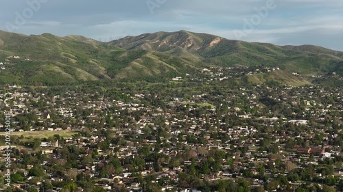 Wide aerial of Wasatch Mountain Range and Bountiful Utah homes in foothills on sunny spring day
