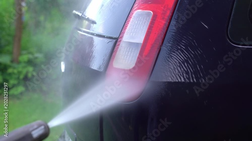Washing car headlight with pressure washer outdoors. High pressure car wash. Car wash