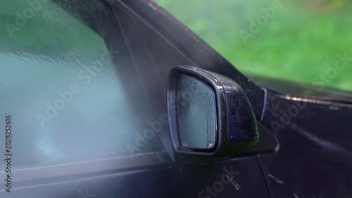 Washing car mirror with pressure washer outdoors. High pressure car wash. Car wash